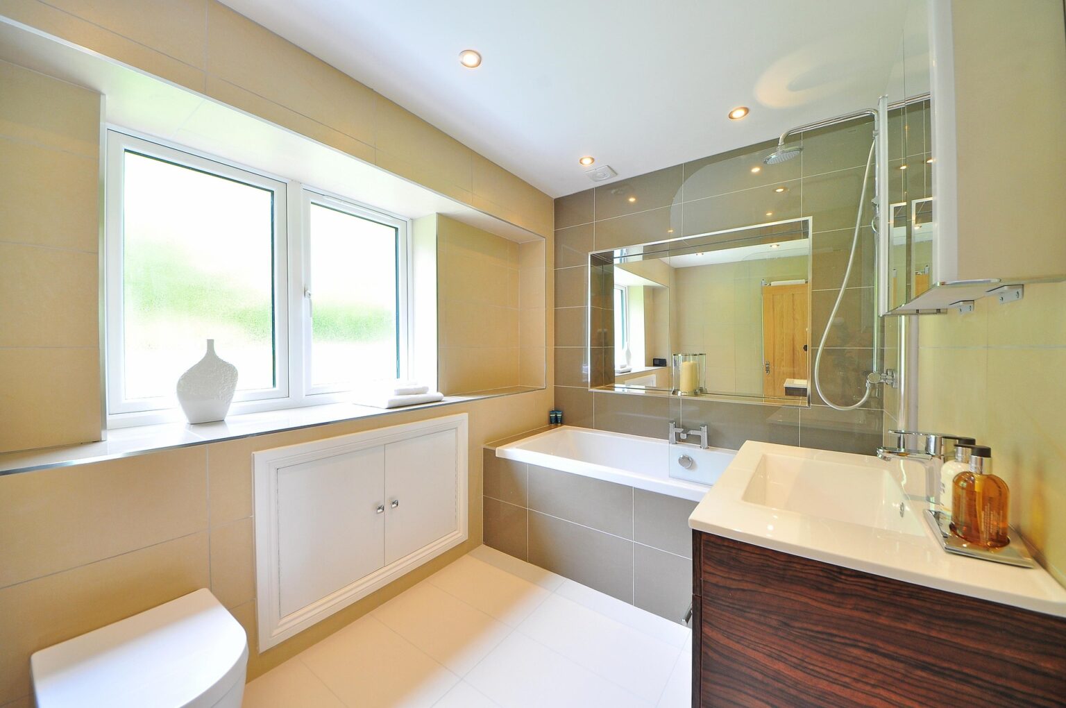 Baño reformado con bañera, ventana y mueble moderno en proyecto de reforma de baño realizado por SJD Reformas en Madrid.