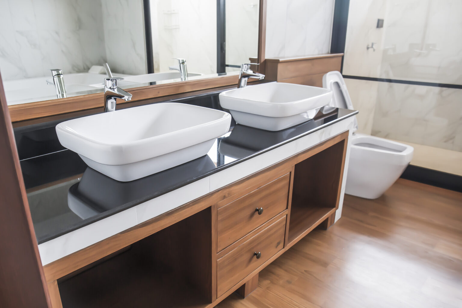 Mueble de baño con doble lavabo sobre encimera y acabado en madera instalado en una reforma de baño realizada por SJD Reformas en Madrid.